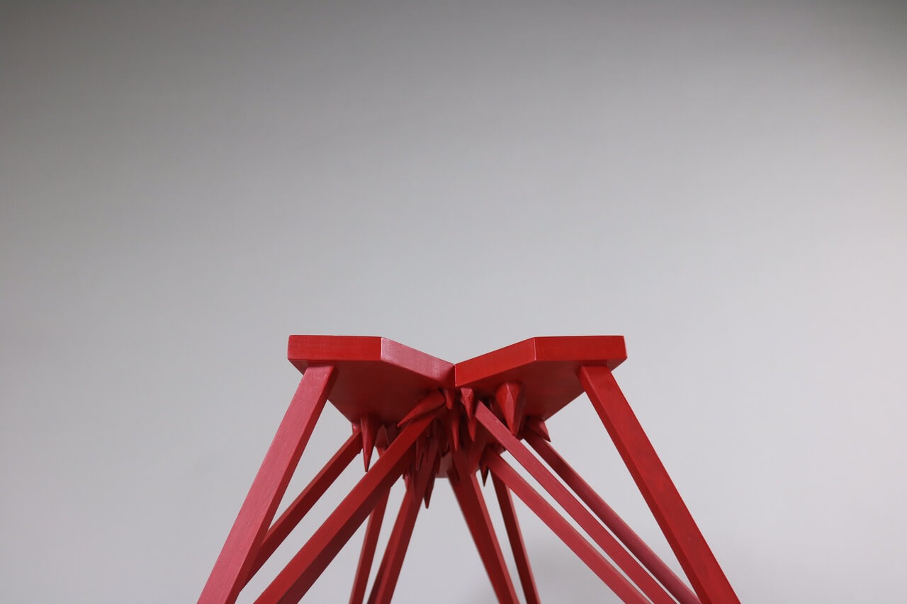 red wooden stool, with spikes underneath